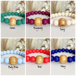 May include: Six silicone bracelets with a wooden bead in the center. The bracelets are in the colors green, burgundy, ivory, baby blue, red, and navy.