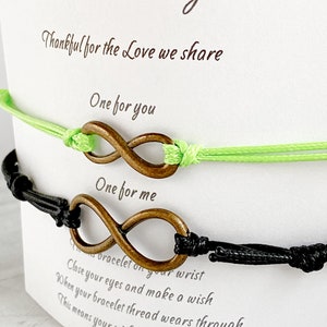 May include: Two infinity symbol bracelets, one black and one green, with a card that reads "Father and Daughter" and "Thankful for the Love we share." The card also says "One for you" and "One for me." The card explains that when the bracelet thread wears through, it means your wish may soon come true.