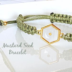 Può includere: Bracciale in macramè verde oliva con un ciondolo esagonale dorato. Il ciondolo presenta un centro bianco con un piccolo seme di senape. Il bracciale ha una chiusura scorrevole regolabile. Il testo sull'immagine recita "Mustard Seed Bracelet."