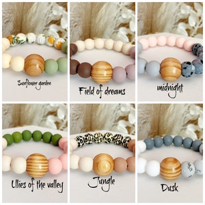May include: Six different silicone bracelets with wooden beads. The bracelets are in various colors and patterns, including sunflower garden, field of dreams, midnight, lilies of the valley, jungle, and dusk.