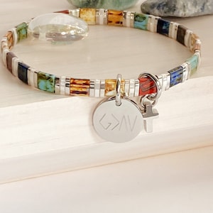 May include: A colorful beaded bracelet with a silver charm that says "G>A" and a small silver cross charm.