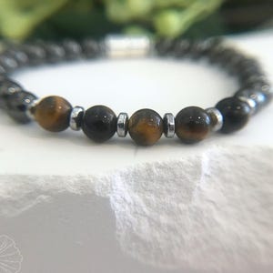 May include: A beaded bracelet with brown tiger's eye and black hematite beads separated by silver spacers.