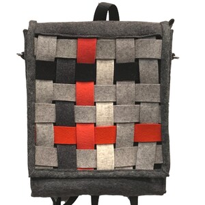 May include: A grey felt backpack with a woven design featuring red, white and black strips. The backpack has adjustable straps.