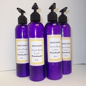 May include: Five purple bottles of hand and body lotion with black pump tops. Each bottle has a white label with the text "JENTO SOAPS" and "Hand & Body Lotion Patchouli" in black text.