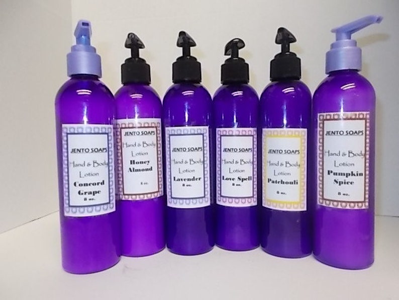 May include: Six purple bottles of hand and body lotion with different scents: Concord Grape, Honey Almond, Lavender, Love Spell, Patchouli, and Pumpkin Spice. Each bottle has a pump dispenser and a white label with the brand name "JENTO SOAPS" and the scent name.