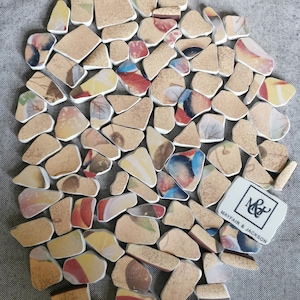 May include: A mosaic coaster composed of irregular, tan ceramic fragments, each displaying colourful abstract patterns. A small, rectangular piece with the text "MAYFAIR & JACKSON" and a logo is included.