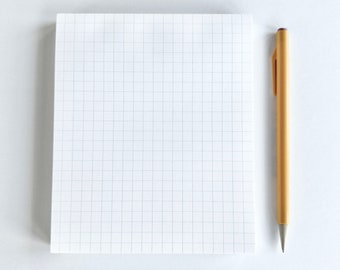 May include: A white gridded notepad with a yellow pen on a white surface.