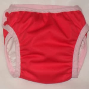 May include: Red swim diaper with pink trim and a red button on the side.
