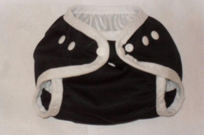 May include: Black cloth diaper with white trim and snap closures.
