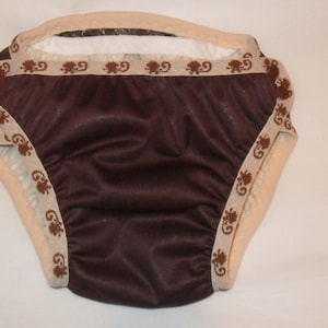 May include: Brown reusable cloth diaper with a white trim and brown patterned trim. The diaper has a white inner lining.