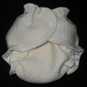 Puede incluir: Pa&ntilde;al de tela blanco con dos broches blancos. El pa&ntilde;al est&aacute; hecho de una tela suave y texturizada.