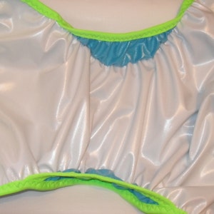 May include: A white and blue reusable cloth diaper with a green trim. The diaper is made of a shiny, waterproof material.