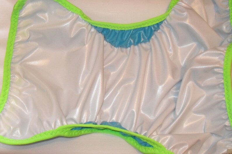 May include: A white and blue reusable cloth diaper with a green trim. The diaper is made of a shiny, waterproof material.