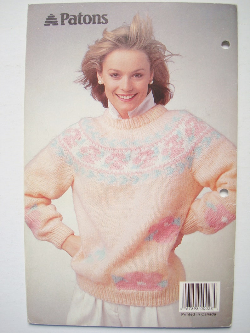 Peut inclure: Un pull rose avec un motif blanc et bleu. Le pull est fabriqu&eacute; par Patons.