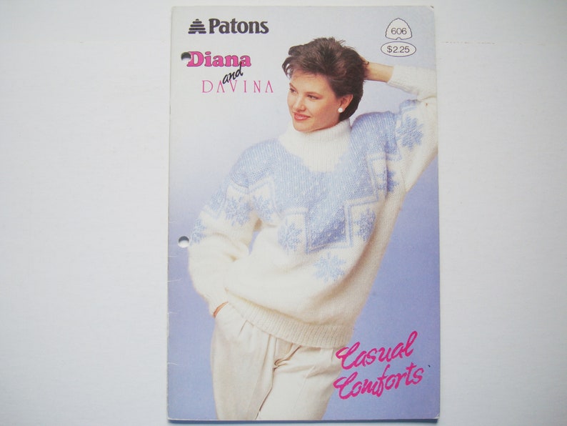 Peut inclure: Un pull en tricot blanc et bleu avec un motif de flocon de neige. Le pull est port&eacute; par une femme aux cheveux bruns courts. Le texte "Diana and Davina" est imprim&eacute; sur la page. Le texte "Casual Comforts" est imprim&eacute; en rose sur la page.