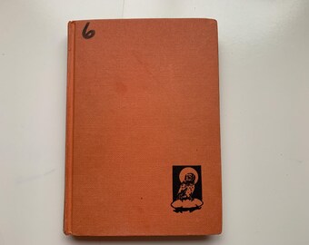 May include: An orange hardback book with a textured cover. The number "6" is written in black marker on the top left corner. A black and white illustration of an owl on a cloud is in the bottom right corner.