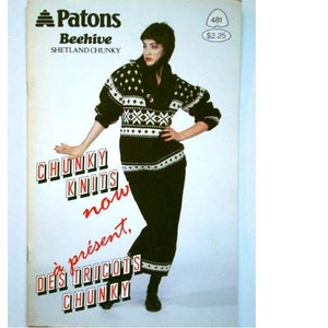 Peut inclure: Une brochure de modèles de tricot avec une femme portant un pull et une jupe à motifs noirs et blancs. Le texte de la couverture est "Patons Beehive Shetland Chunky" et "Chunky Knits now present, Des Tricots Chunky".