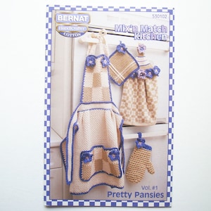 May include: Crochet pattern booklet for a kitchen apron, tea towel, and pot holder. The pattern is called "Pretty Pansies" and is part of the "Mix'n Match Kitchen" series. The pattern is made with Bernat Handicrafter Cotton yarn.