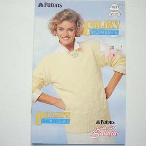 Può includere: Un libretto vintage di modelli di maglieria Patons con una donna che indossa un maglione giallo. La copertina presenta il testo "GOLDEN MOMENTS" e "OCCASIONS EN OR". Il libretto è per il filato "Cotton Sahara".