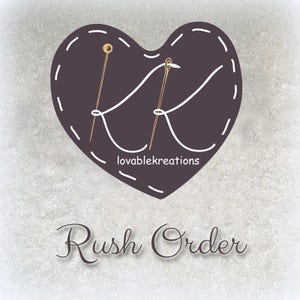 May include: A heart-shaped logo with a stitched border, featuring the letters "K" intertwined with a needle and thread design. The text "lovablekreations" is below the heart, and the words "Rush Order" are written in a script font.