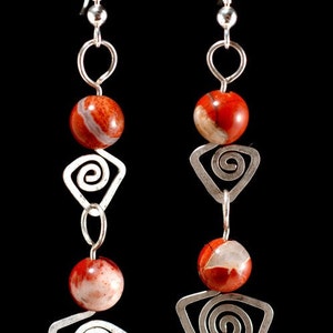 May include: Silver earrings with red and white stone beads and silver spiral designs.