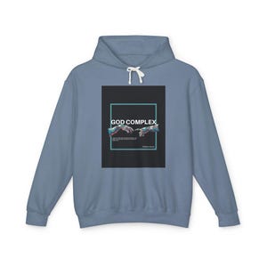 May include: A blue hooded sweatshirt with a graphic print of two hands reaching towards each other. The graphic is set against a black background with the text "GOD COMPLEX" in white.