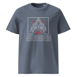 May include: A dark blue t-shirt with a white graphic of a woman with her hands in a prayer position. The graphic is surrounded by a white square and the text "GOD COMPLEX" is repeated three times in white letters.