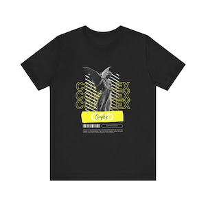 May include: Black t-shirt with a graphic of a stone angel with wings and the word "Complex" in yellow. The text "Complex" is repeated multiple times in yellow.