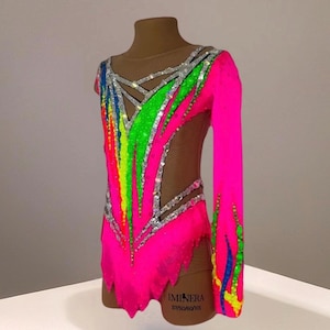 May include: A long-sleeved leotard in neon pink featuring a vibrant rainbow gradient of green, yellow, and blue accents. The garment is embellished with silver crystals and includes sheer nude mesh panels at the neckline and sides, with the text IMINERA 57/50/60/105 printed on the lower hip.