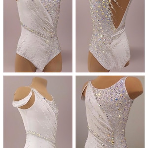 May include: White leotard with sparkling crystal embellishments. The leotard features a unique asymmetrical design with a diagonal pattern of crystals and a low back. Perfect for dance or gymnastics performances.