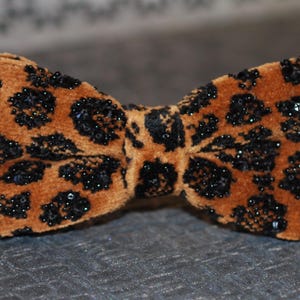 May include: A brown velvet bow tie with a black leopard print and black sequins.