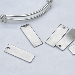 May include: Five silver metal rectangular tags with two holes each. The tags are blank and ready for personalization.