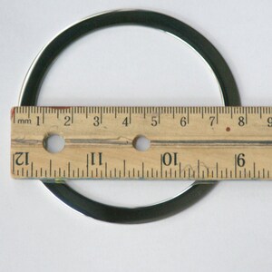 Pu&ograve; includere: Un anello di metallo argentato con un diametro di circa 18 cm, misurato con un righello.