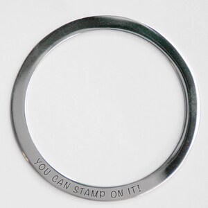 Pu&ograve; includere: Un anello in metallo argentato con le parole "You Can Stamp On It!" incise all'esterno.