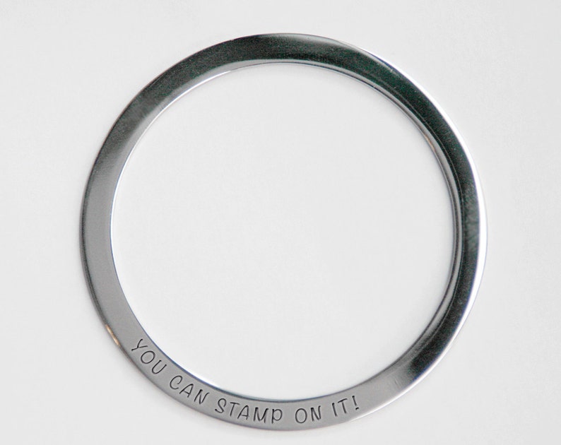 Pu&ograve; includere: Un anello in metallo argentato con le parole "You Can Stamp On It!" incise all'esterno.
