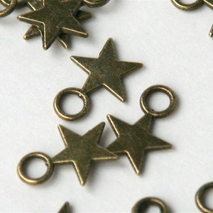 May include: A group of antique gold star charms with jump rings. The charms are perfect for adding a touch of vintage style to jewelry making projects.