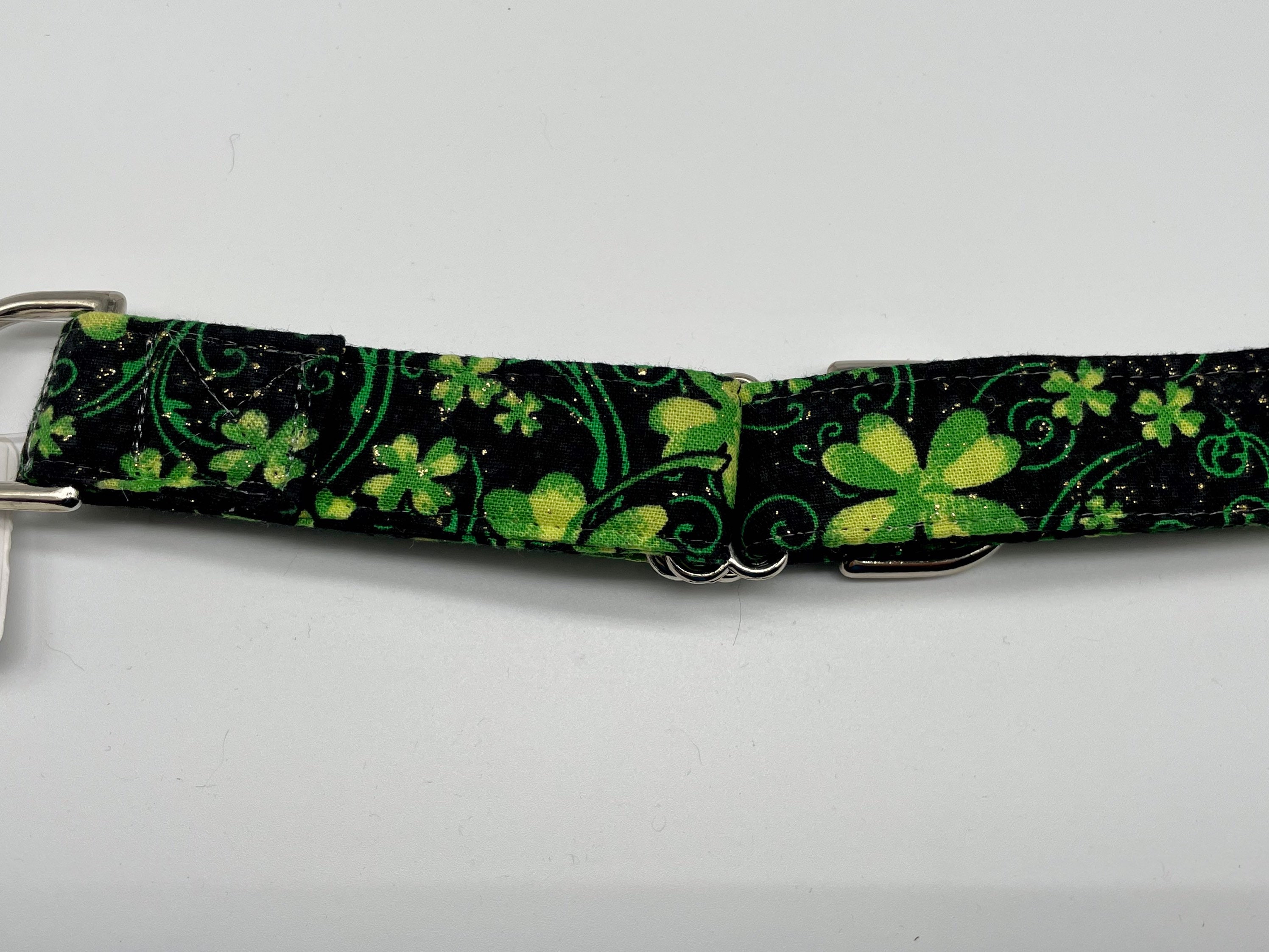 Medium 1 inch martingale collar the background is black with green shamrocks and gold glitter.