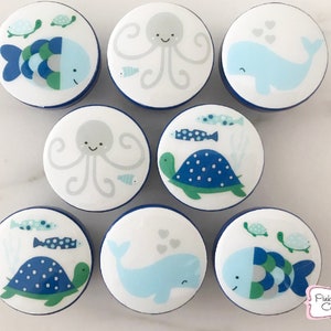 以下が含まれることがあります： クジラ、タコ、カメなど、さまざまな海の生き物のデザインが施された、青と白のセラミックノブ8個セットです。