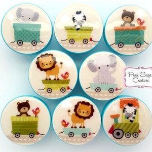 Puede incluir: Conjunto de 8 pomos redondos de cerámica blanca con ribete azul. Cada pomo presenta un animal diferente en un tren, incluyendo un león, una cebra, un elefante y un oso. Los vagones del tren son verdes, amarillos y azules. Los pomos son perfectos para añadir un toque caprichoso a cualquier habitación.