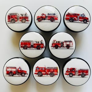 Puede incluir: Conjunto de siete pomos de camión de bomberos rojos con ribetes negros. Cada pomo presenta una imagen diferente de un camión de bomberos con detalles blancos.