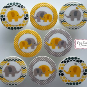 Peut inclure: Huit boutons ronds décoratifs jaunes et gris avec un motif d'éléphant bébé. Les boutons présentent un éléphant jaune avec un oiseau sur le dessus, un éléphant gris avec un éléphant jaune et un éléphant gris avec un oiseau sur le dessus. Les boutons sont parfaits pour ajouter une touche de fantaisie à n'importe quelle pièce.