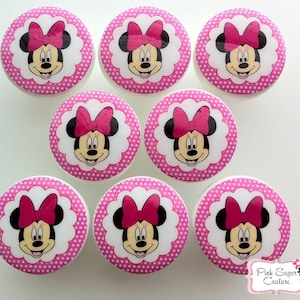 May include: Set of eight pink and white polka dot round drawer knobs with a white scalloped border and a cartoon image of Minnie Mouse in the center.