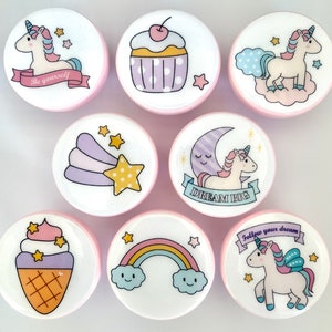 Op de afbeelding: Set van 10 ronde, kleurrijke stickers met eenhoornontwerpen. De stickers tonen eenhoorns met sterren, regenbogen en de tekst "Wees jezelf" en "Droom groot".