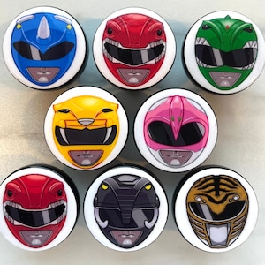 Könnte beinhalten: Set mit 10 bunten Power Rangers-Rundenknöpfen. Jeder Knopf zeigt einen anderen Ranger mit einem einzigartigen Design und Farbschema. Zu den Rangern gehören der Rote Ranger, der Blaue Ranger, der Schwarze Ranger, der Gelbe Ranger, der Rosa Ranger, der Grüne Ranger, der Weiße Ranger und das Logo der Mighty Morphin Power Rangers.