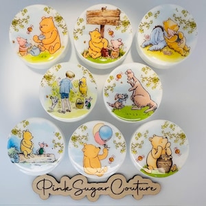 May include: Set of 8 round ceramic Winnie the Pooh themed magnets. Each magnet features a different scene from the Winnie the Pooh stories. The magnets are white with a glossy finish.