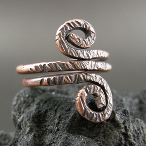 May include: A copper ring with a textured finish and a double spiral design.