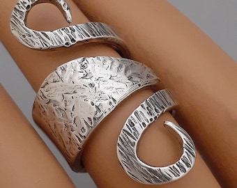 May include: A silver ring with a textured, hammered finish. The ring is designed in a spiral shape with a large open loop at the top.