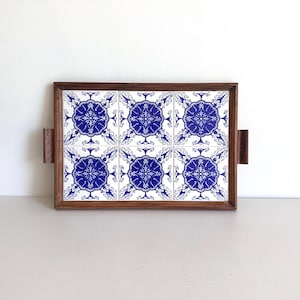 May include: A wooden serving tray with blue and white tile insets. The tray has two handles on the sides.