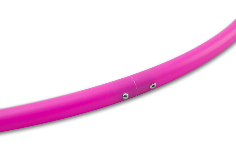 Op de afbeelding: Een roze plastic hoelahoep met twee zilveren metalen accenten.