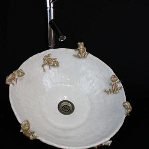 May include: White ceramic sink with a chrome faucet and frog figurines around the rim.